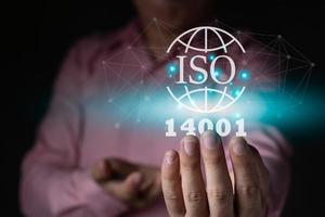 un' uomo d'affari Tenere il iso 14001 ambiente icona, grafico leggero Internet globale icona, standard qualità documento controllo per organizzazione e industria gestione prodotti, copia spazio per testo foto