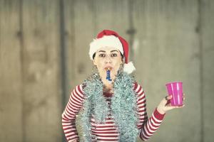 giovane attività commerciale donna indossare un' rosso cappello e soffiaggio festa fischio foto