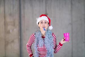 giovane attività commerciale donna indossare un' rosso cappello e soffiaggio festa fischio foto