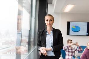 ritratto di giovane attività commerciale donna a ufficio con squadra su incontro nel sfondo foto