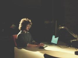 uomo Lavorando su computer nel buio ufficio foto