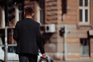 uomo d'affari con valigia passeggiate giù il strada foto