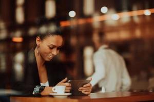 donna nel un' caffè negozio bevanda caffè visto attraverso bicchiere con riflessi come essi sedersi a un' tavolo chat e ridendo foto