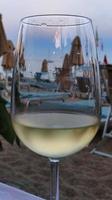 un' bicchiere di raffreddato bianca vino nel un' ristorante di il mare durante il estate di 2022 foto