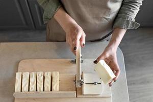 un' donna fa fatto a mano naturale sapone.il finito sapone è tagliare in pezzi utilizzando speciale macchina. casa spa. piccolo attività commerciale foto