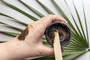 nella mano di una donna c'è un barattolo con uno scrub per il corpo a base di ingredienti naturali. cosmetici fatti a mano. terme di casa. foto