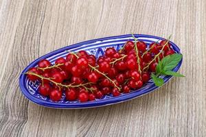 rosso ribes nel un' ciotola su di legno sfondo foto