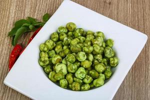 wasabi piselli nel un' ciotola su di legno sfondo foto