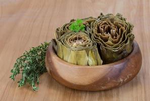 bollito carciofi nel un' ciotola su di legno sfondo foto