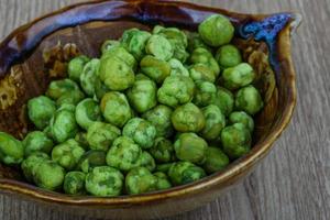 wasabi piselli nel un' ciotola su di legno sfondo foto