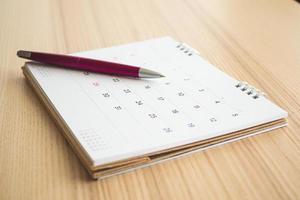 calendario pagina con penna su legna tavolo sfondo foto