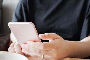 donna con anello di diamanti a portata di mano utilizzando lo smartphone nel ristorante caffetteria foto