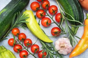 impostato di diverso di stagione verdure su un' grigio calcestruzzo sfondo. pomodoro zucchine cipolla aglio rosmarino Pepe spezie. foto