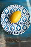 giallo fresco Limone su il piatto con blu modello su di legno sfondo foto