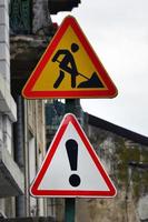 strada segni con un esclamazione marchio e un' uomo scavando il terra. strada lavori siamo in corso foto