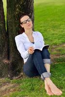 giovane donna che legge un libro nel parco foto