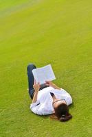 giovane donna che legge un libro nel parco foto