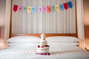 festeggiare compleanno, sorpresa nel letto con contento compleanno bandiera e asciugamano torta. foto