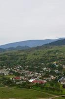 un' bellissimo Visualizza di il villaggio di mezhgorye, carpazi regione. un' lotto di Residenziale edifici circondato di alto foresta montagne e lungo fiume foto