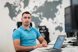 giovane uomo seduta nel ufficio e Lavorando su del desktop pc. uomo d'affari guardare a computer tenere sotto controllo mentre Lavorando nel ufficio. foto