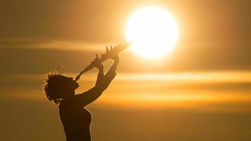 donna giocando un' sassofono a il sole foto