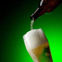 birra in dinamica su sfondo verde sfumato foto
