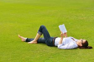 giovane donna che legge un libro nel parco foto