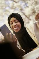 africano donna utilizzando smartphone indossare tradizionale islamico Abiti foto