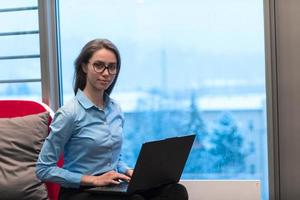 un' giovane donna seduta nel un' moderno spazio mentre Lavorando su un' progetto su un' il computer portatile. selettivo messa a fuoco foto