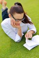 giovane donna che legge un libro nel parco foto