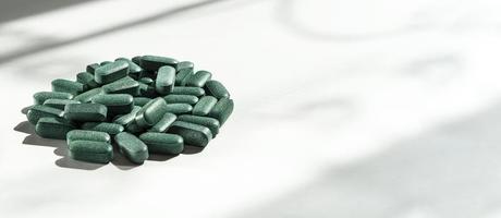 pillole di clorella, spirulina, orzo erba su bianca sfondo con buio ombre primo piano e ombra modello nutritivo supplemento, disintossicazione superfood foto