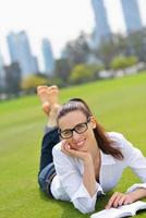 giovane donna che legge un libro nel parco foto