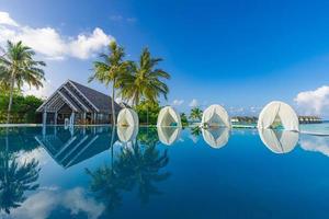 bellissimo lusso ombrello e sedia con all'aperto nuoto piscina nel tropicale spiaggia Hotel ricorrere. Noce di cocco palma alberi a bordo piscina. estate viaggio vacanza sfondo concetto. sorprendente relax, la libertà panoramico foto