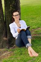 giovane donna che legge un libro nel parco foto