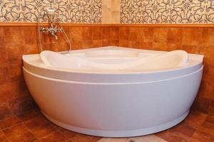 grande bianca vasca da bagno nel un' mezzo di industriale soffitta bagno stile con grunge cemento parete. foto