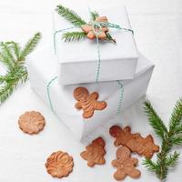 Natale i regali avvolto nel bianca carta e decorato con abete rosso rametti e Pan di zenzero biscotti foto