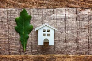 casa del giocattolo e foglia di quercia verde su fondo di legno foto