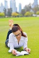 giovane donna che legge un libro nel parco foto