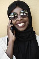 africano donna utilizzando smartphone indossare tradizionale islamico Abiti foto