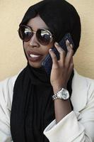 africano donna utilizzando smartphone indossare tradizionale islamico Abiti foto