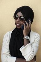 africano donna utilizzando smartphone indossare tradizionale islamico Abiti foto