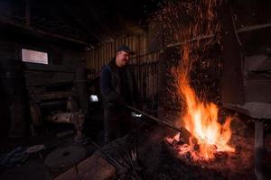 giovane tradizionale maniscalco Lavorando con Aperto fuoco foto