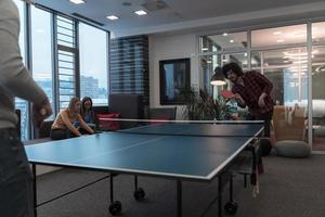 Due giovane inizio su attività commerciale uomo giocando ping pong tennis a moderno creativo ufficio spazio persone gruppo avere incontro e di brainstorming nel sfondo foto