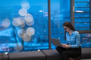 un' giovane donna seduta nel un' moderno spazio mentre Lavorando su un' progetto su un' il computer portatile. selettivo messa a fuoco foto