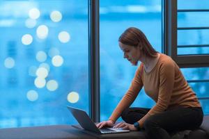 un' giovane donna seduta nel un' moderno spazio mentre Lavorando su un' progetto su un' il computer portatile. selettivo messa a fuoco foto