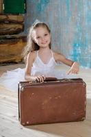 piccola adorabile ballerina in tutù bianco con vecchie valigie vintage foto
