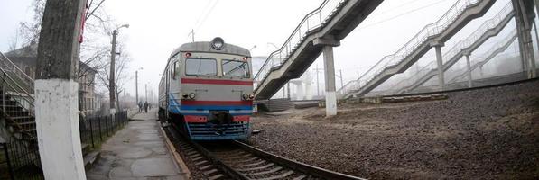 il ferrovia traccia nel un' nebbioso mattina. il ucraino suburbano treno è a il passeggeri stazione. fisheye foto con è aumentato distorsione