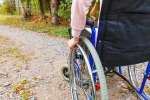 donna con handicap a mano in sedia a rotelle su strada nel parco dell'ospedale in attesa di servizi per i pazienti. ragazza paralizzata irriconoscibile su sedia per invalidi per disabili all'aperto. concetto di riabilitazione. foto