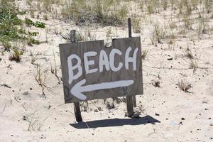 dipinto spiaggia cartello nel il sabbia su il capo foto