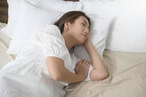 giovane asiatico donna addormentato su il letto nel Camera da letto, contento salutare stile di vita concetto foto